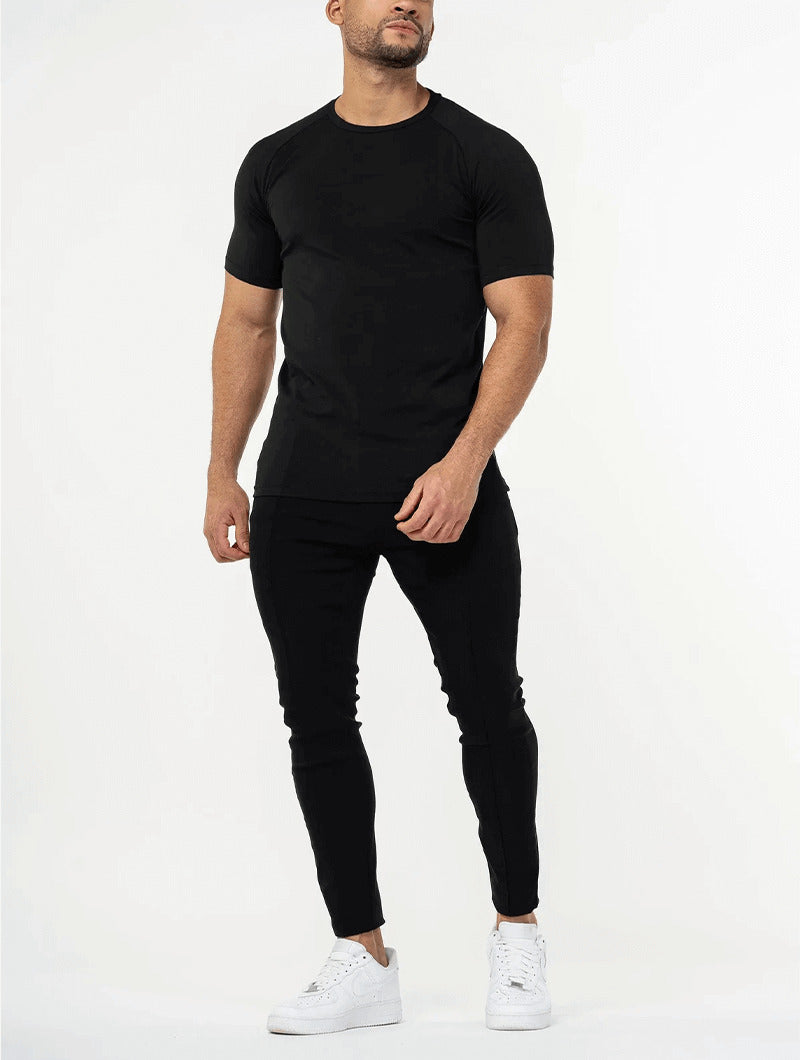 Man wearing a Balinaro Aleano black t-shirt and black pants with white sneakers on a white background