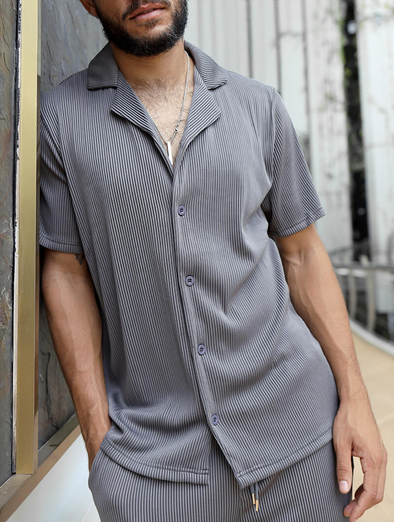 Man wearing a Balinaro Bailey gray striped shirt and pants leaning against a wall.