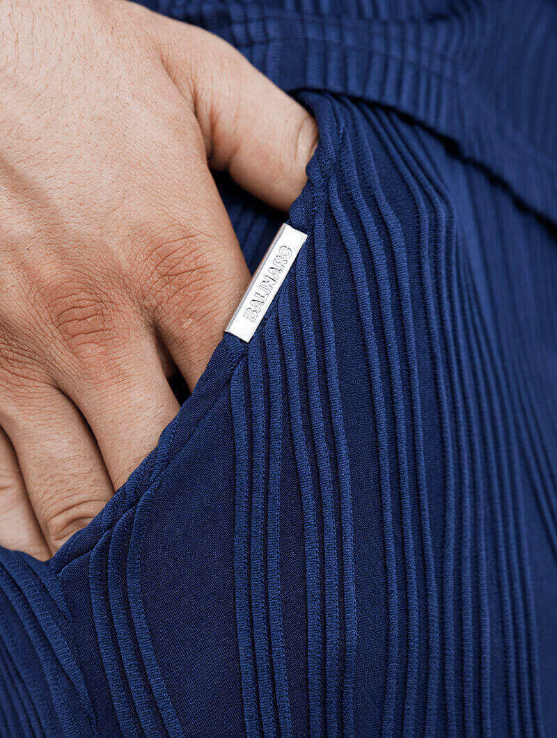 Close-up of a hand holding a blue pleated fabric with a Balinaro Rio Shorts.